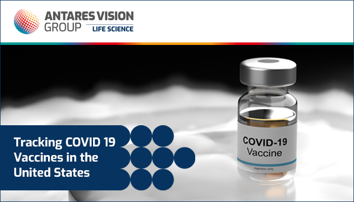 A vial labeled "COVID 19 vaccine" sits on dry ice against a black background.